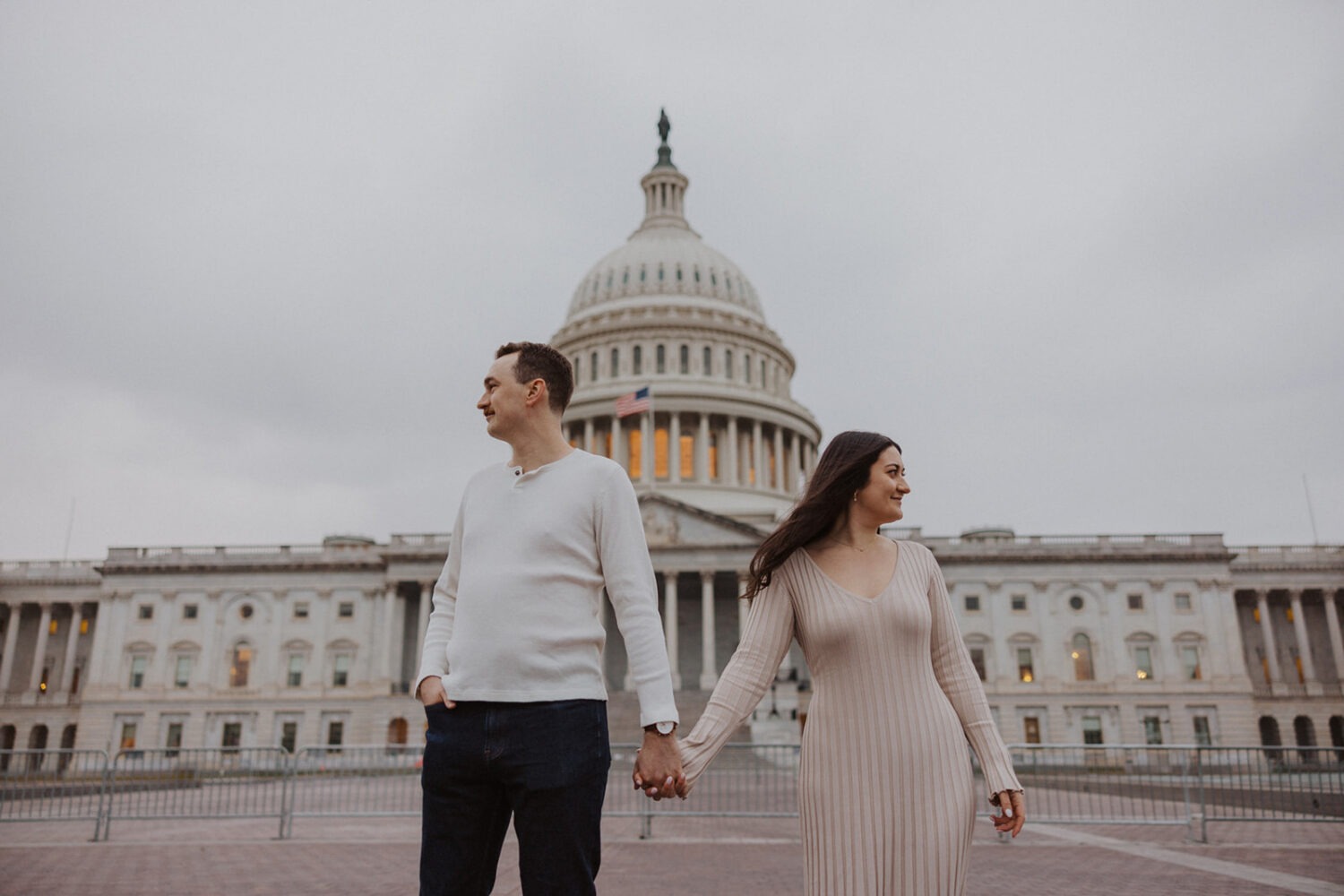 couple hold hands and look in opposite directions in front of Capitol Hill DC