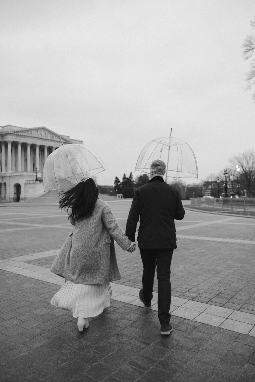 couple walking holding clear umbrellas in Washington DC