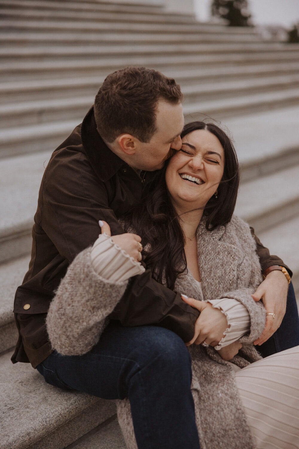 couple kiss and laugh on steps in front of Capitol Hill DC
