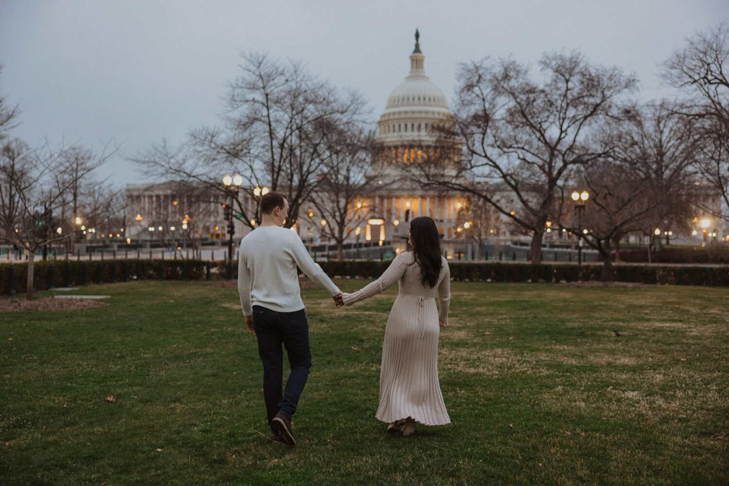 couple walking in the grass with Capitol Hill DC in the background