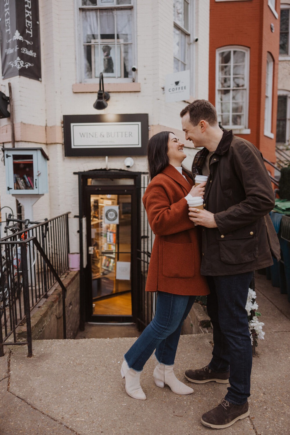 couple embrace outside coffee shop with coffee in hand