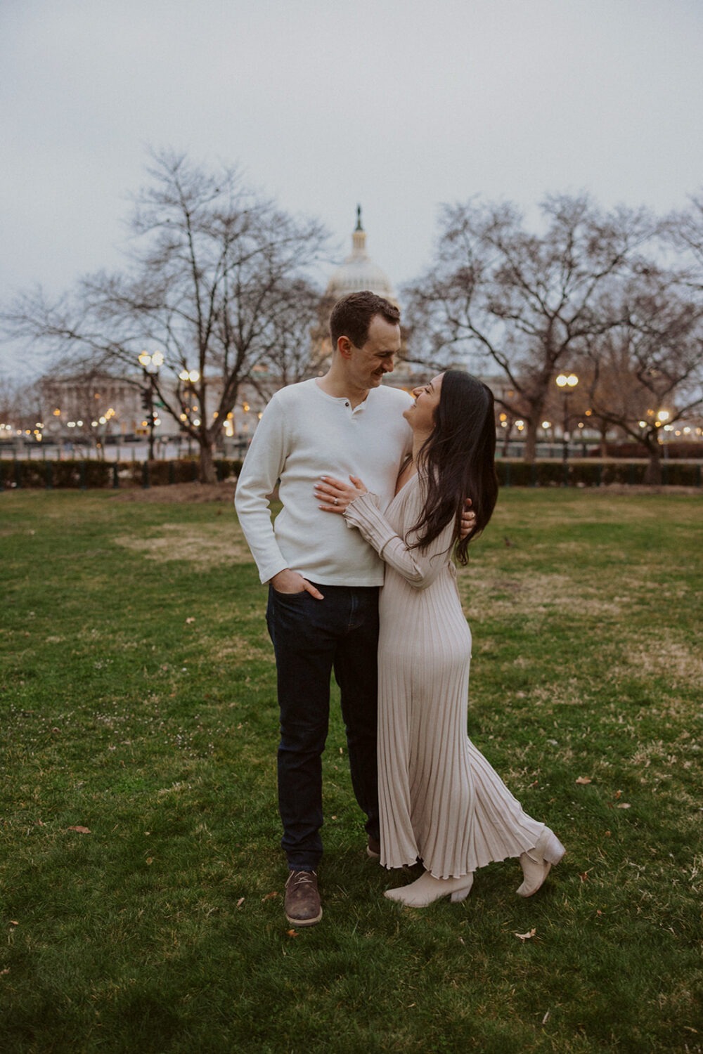 couple pose in the grass with Capitol Hill DC in the background