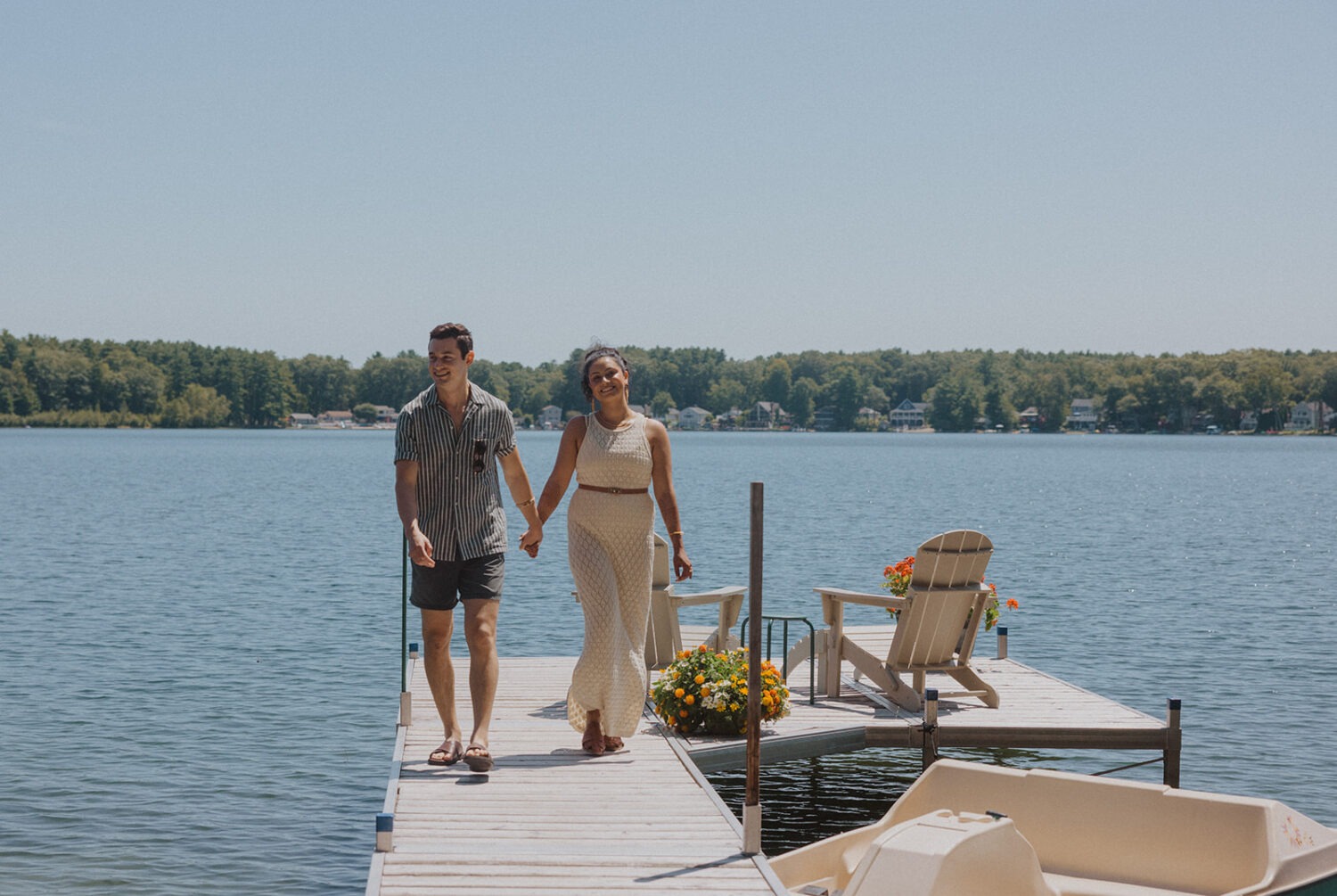 couple walk together on dock at the lake