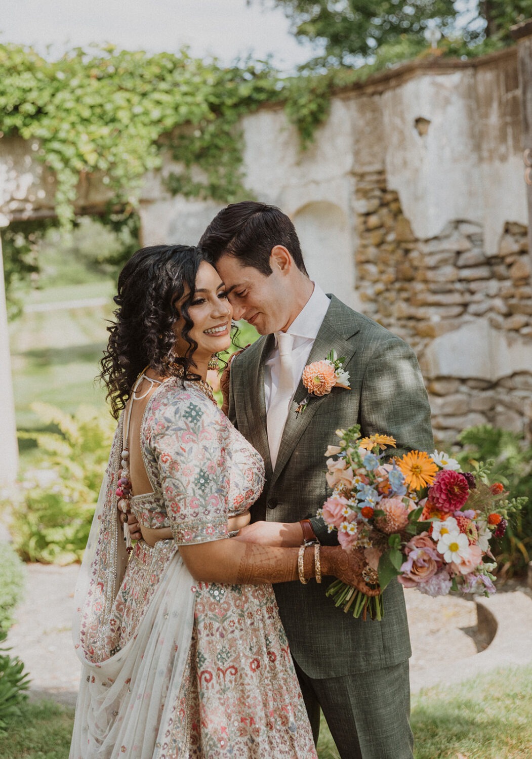 couple pose with flowers and stone wall