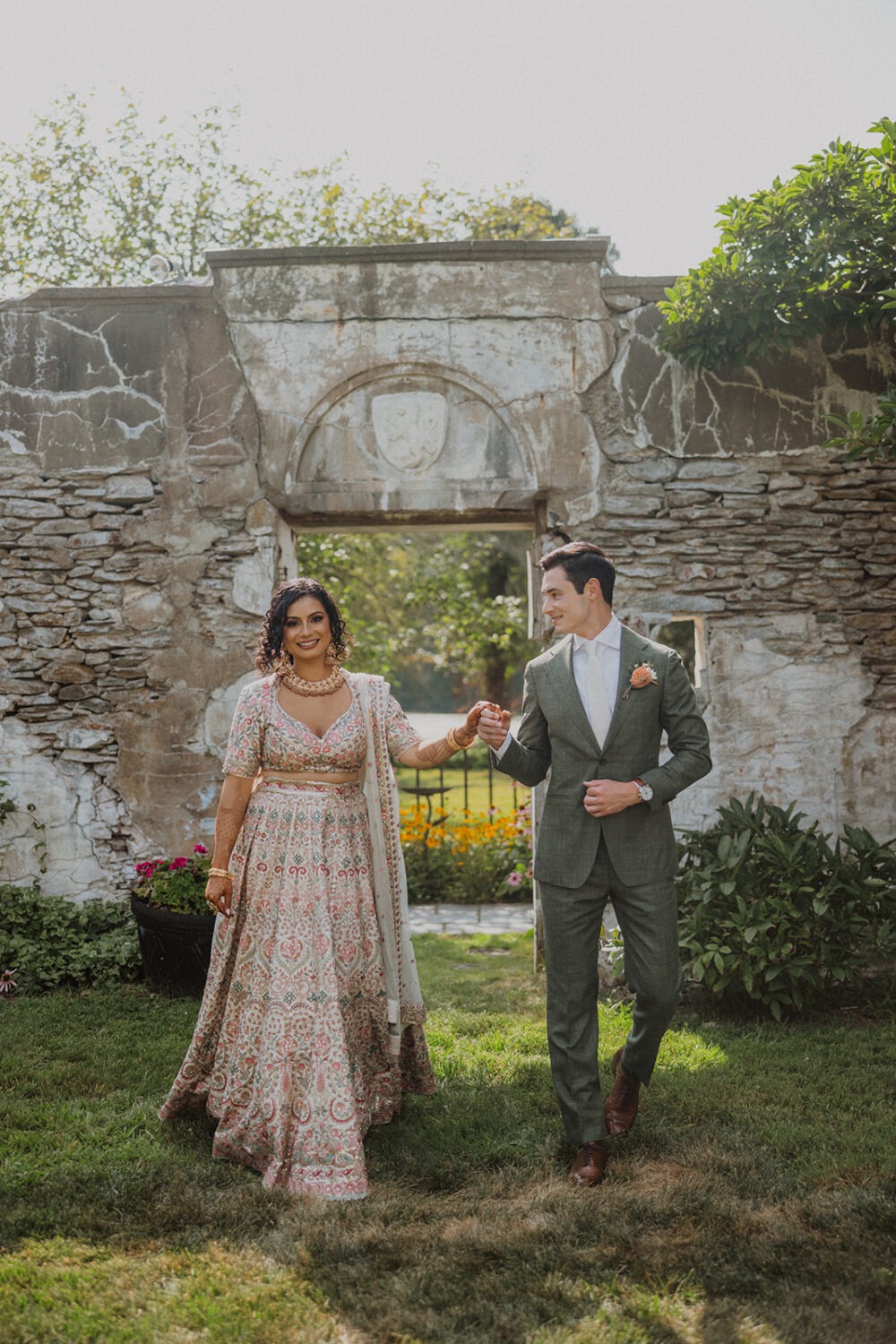 couple walk together hand in hand by stone wall