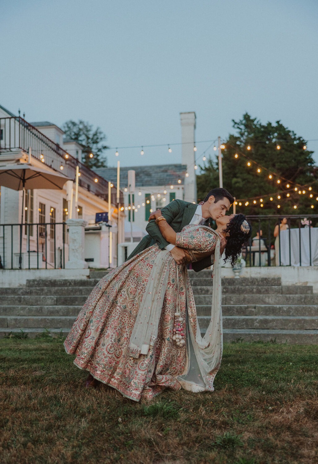 couple kiss in front of stone steps of mansion wedding 