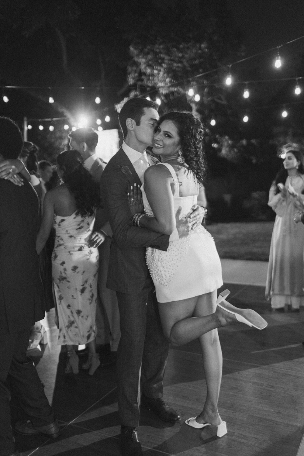 couple embrace as they dance together under the lights during the reception  