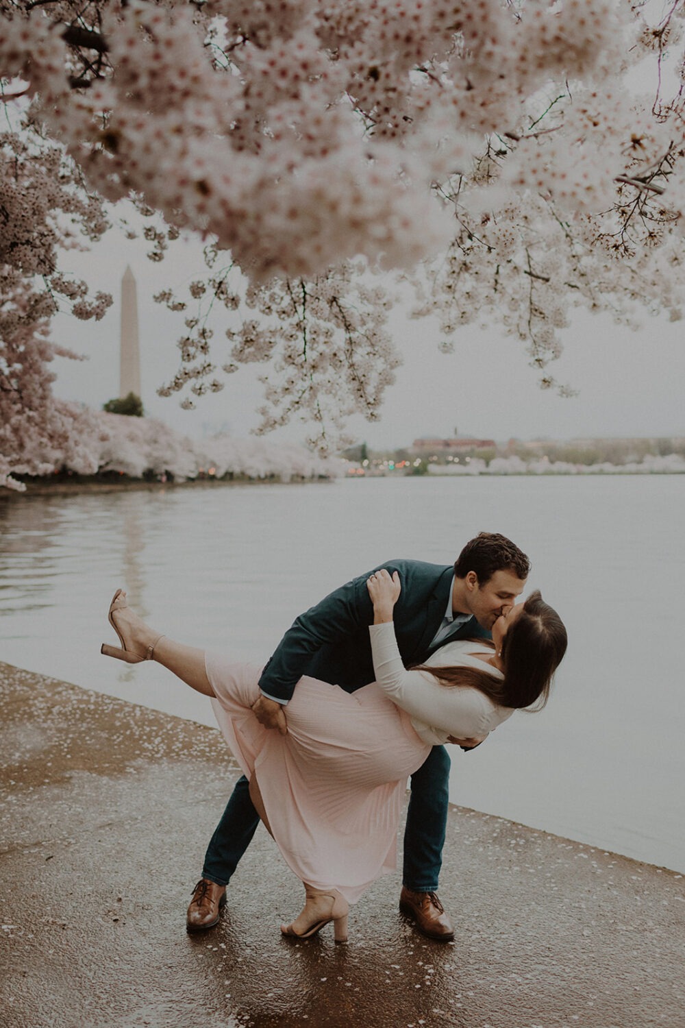 couple pose along the water while taking DC cherry blossom photos
