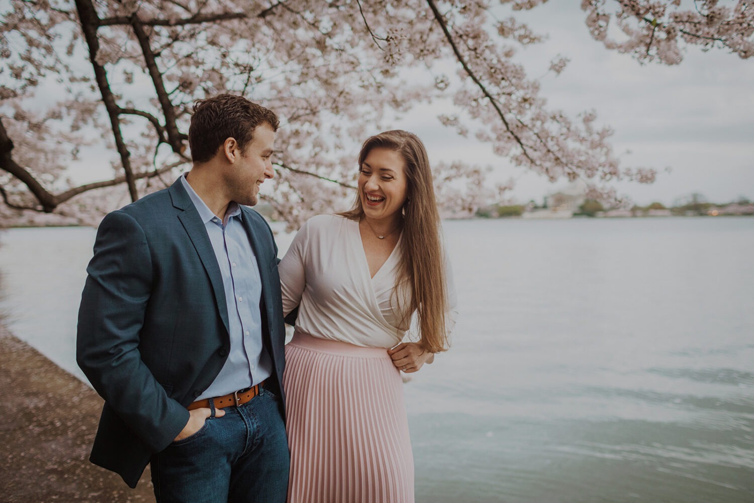 couple pose along the water while taking DC cherry blossom photos
