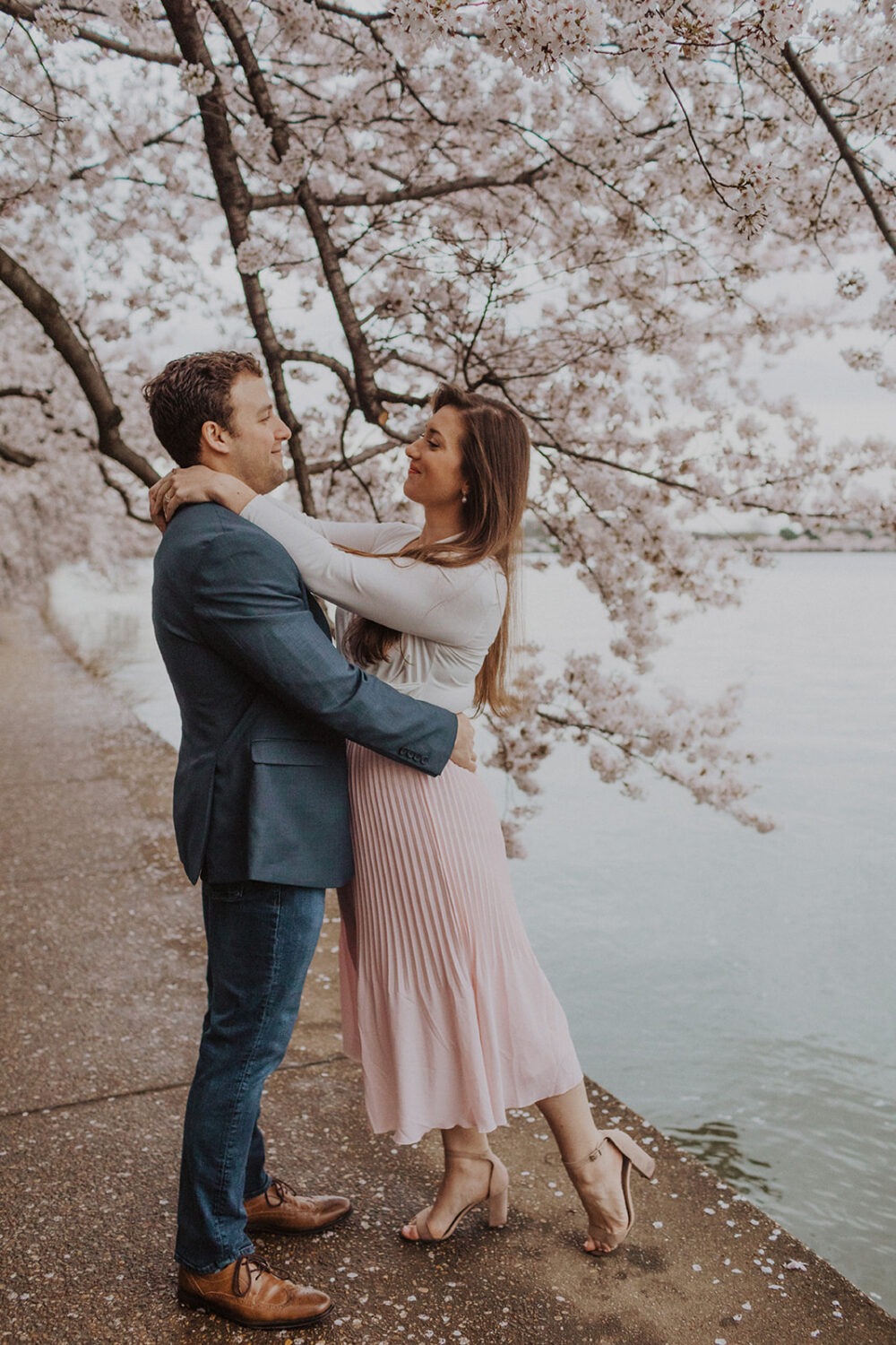couple pose along the water while taking DC cherry blossom photos