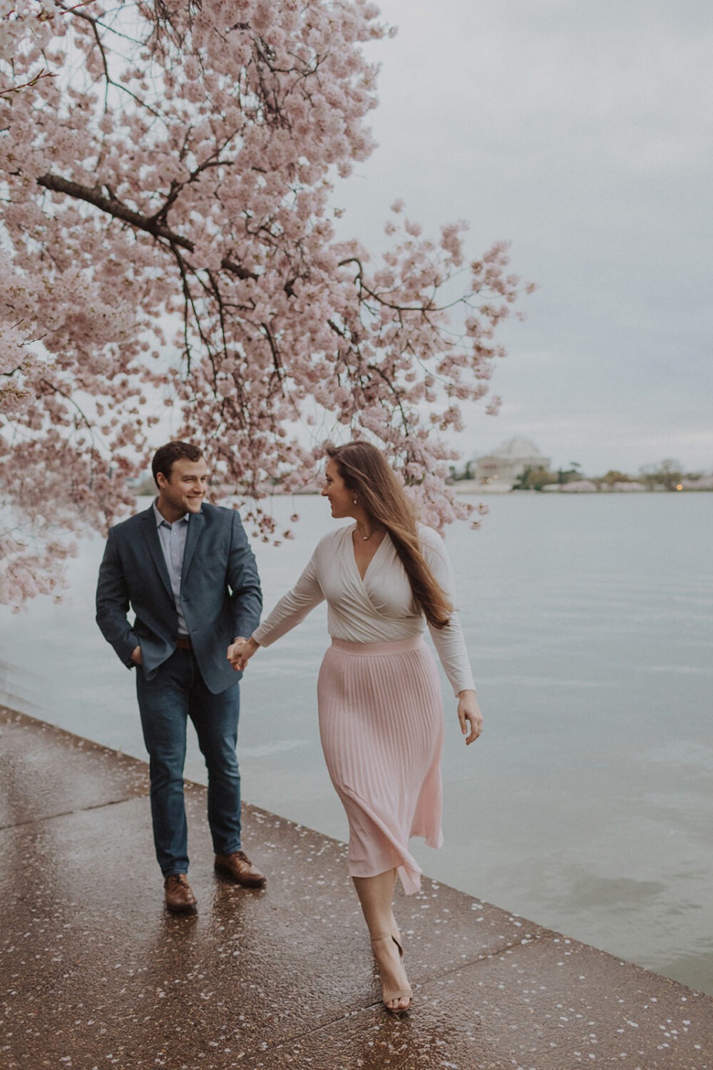 couple walk together holding hands along the water
