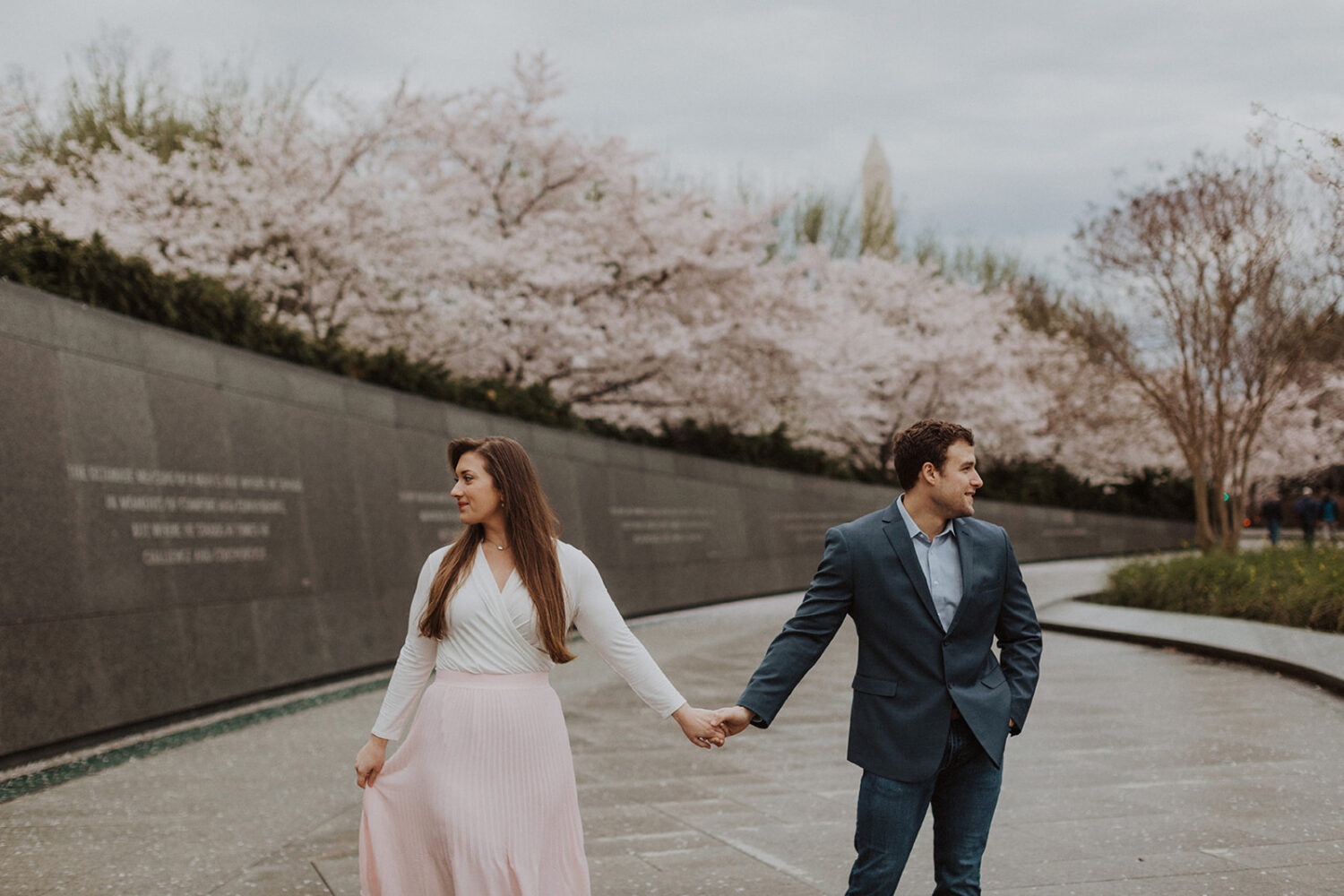 couple hold hands looking in opposite directions