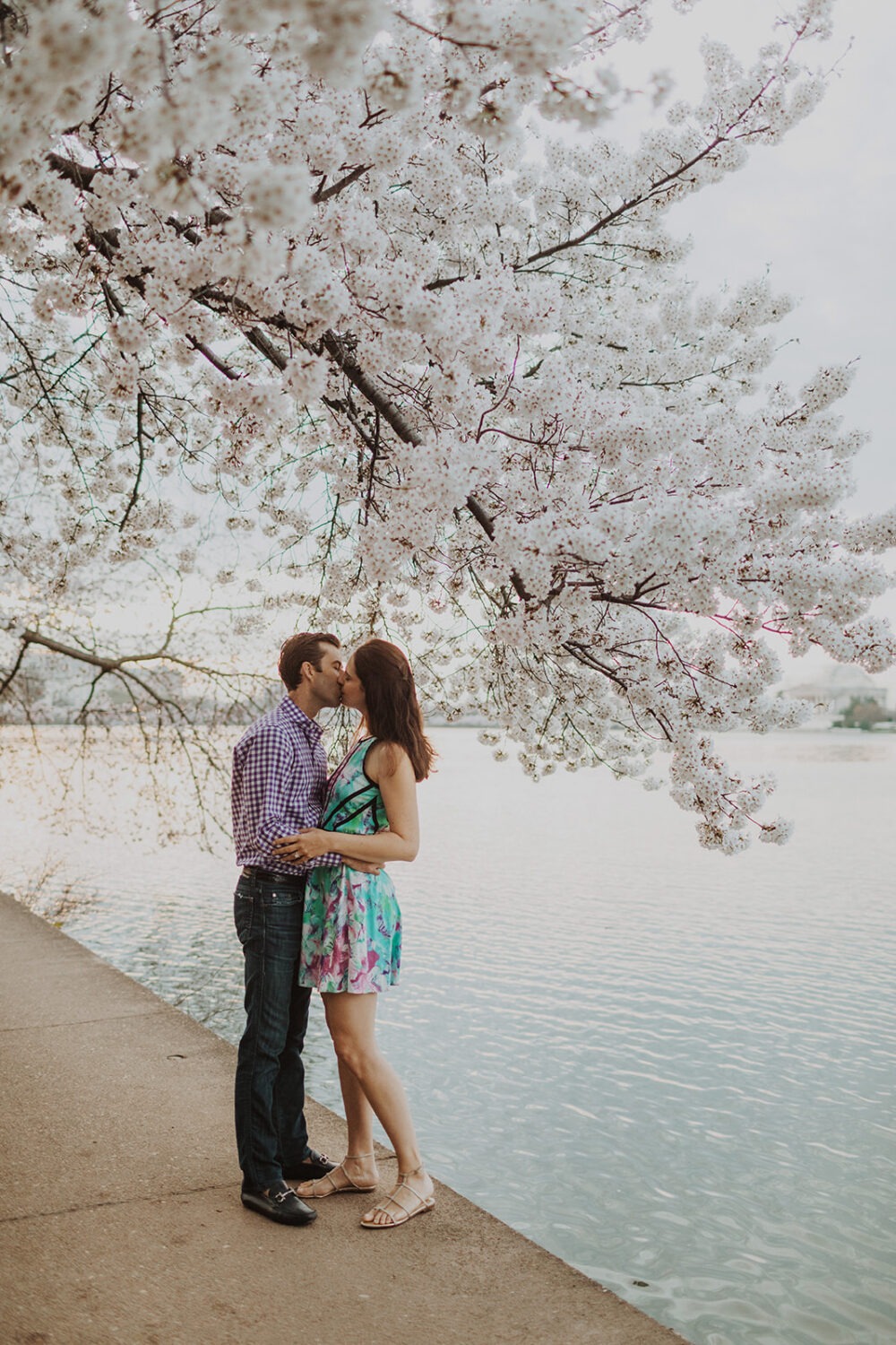couple kissing on ledge overlooking the water