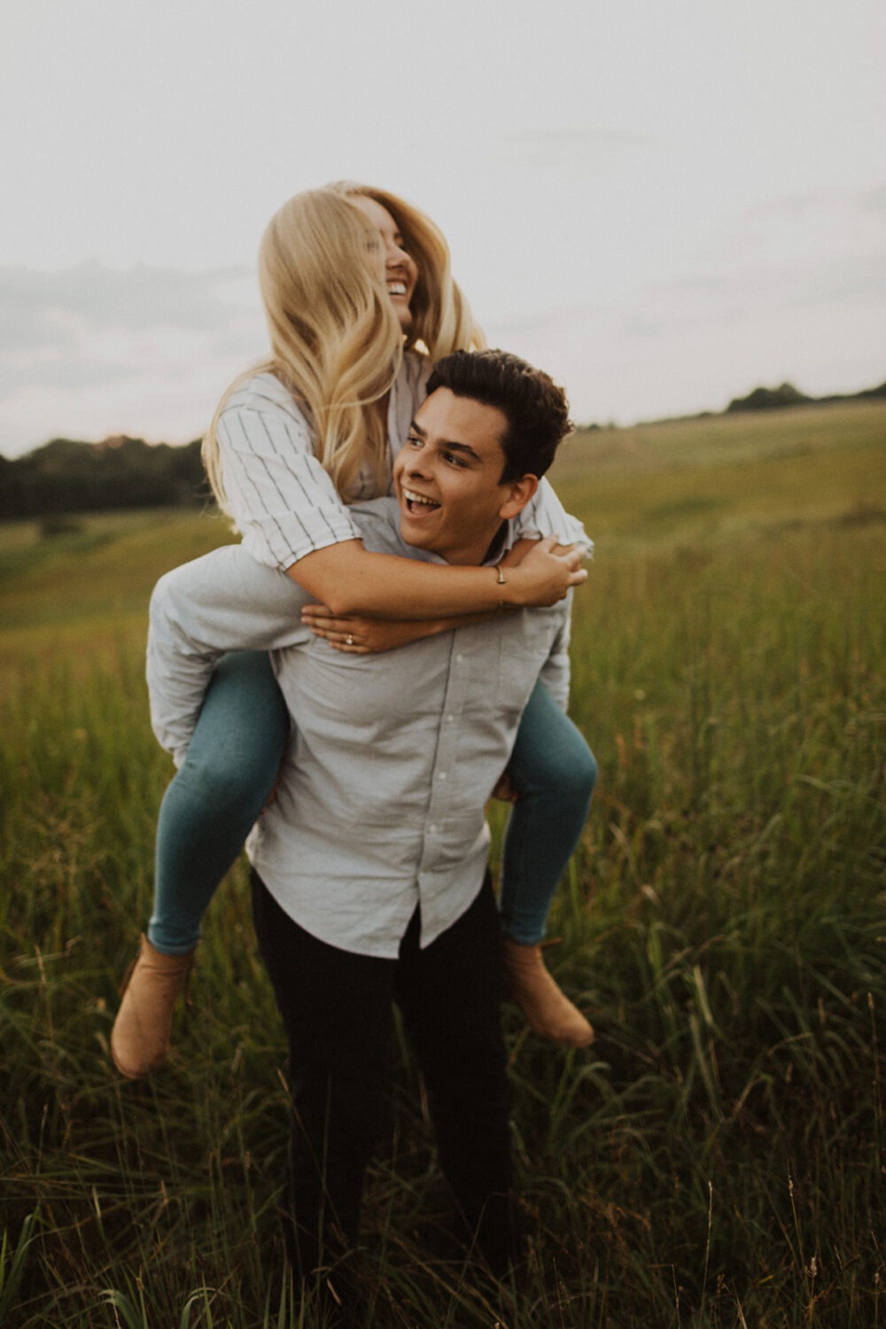 couple do a piggyback pose in grassy field