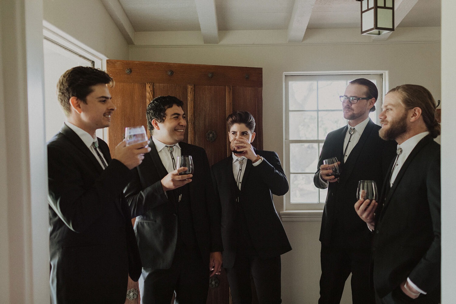 groom and groomsmen posing with drinks
