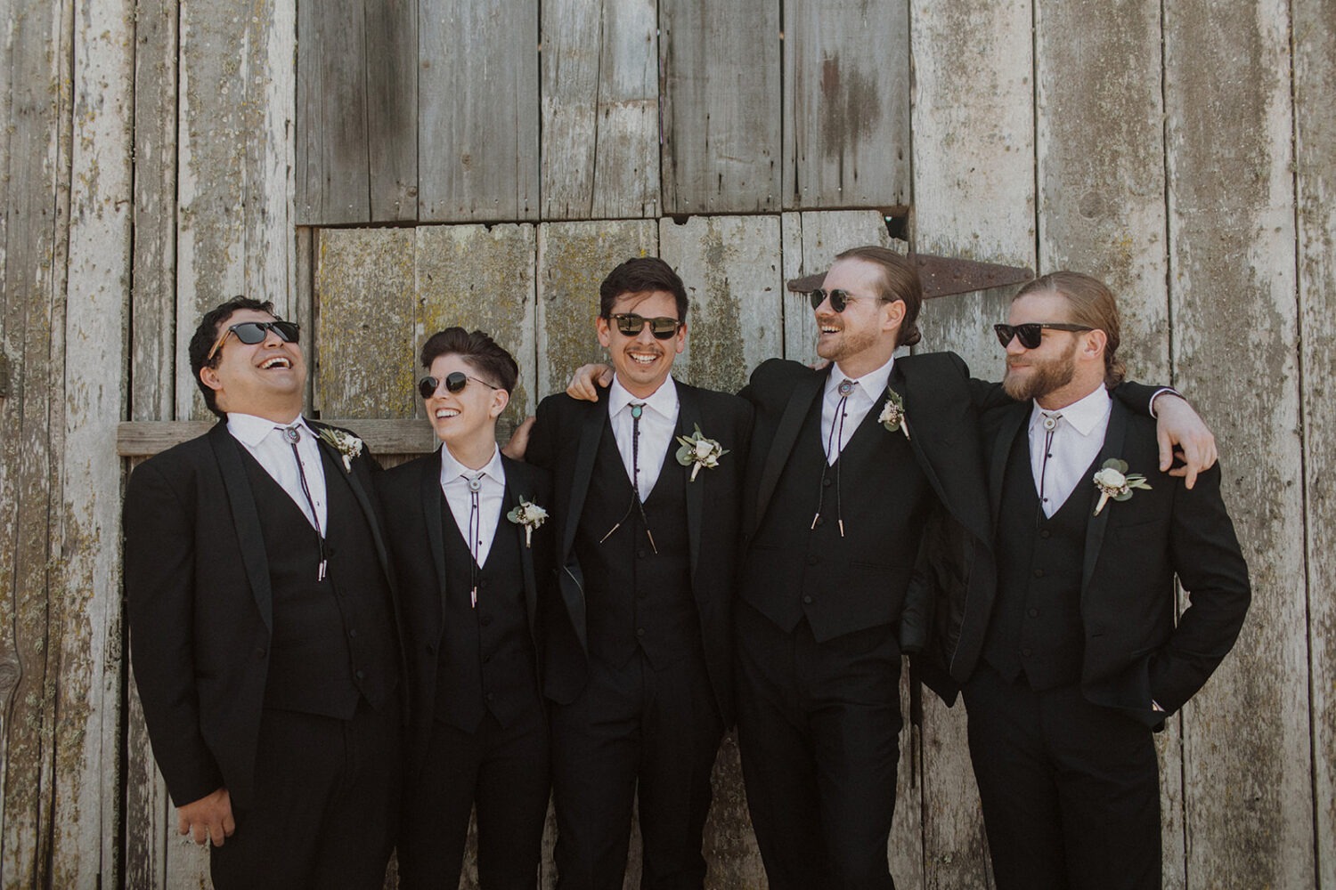groom and groomsmen posing in front of rustic barn