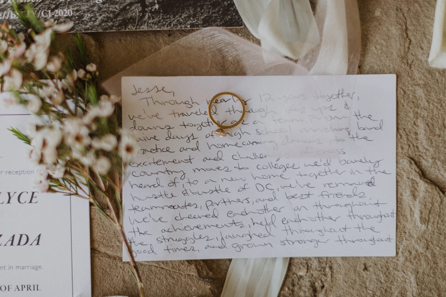 wedding flat lay with handwritten note, spring florals, and ring