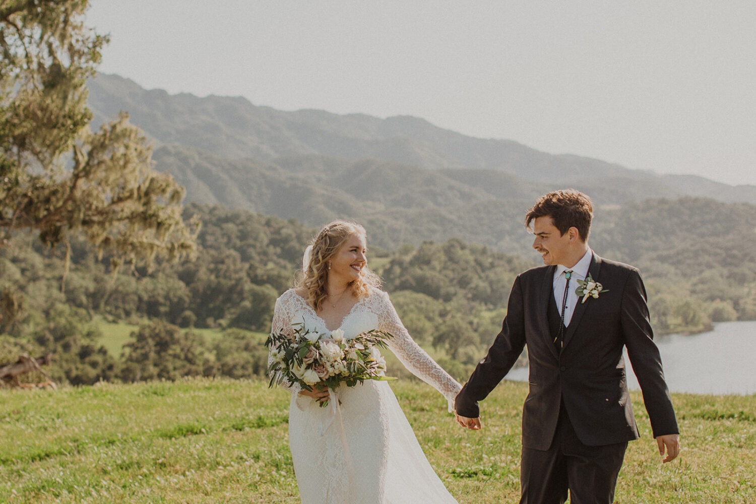 couple walking together holding hands through green grassy field