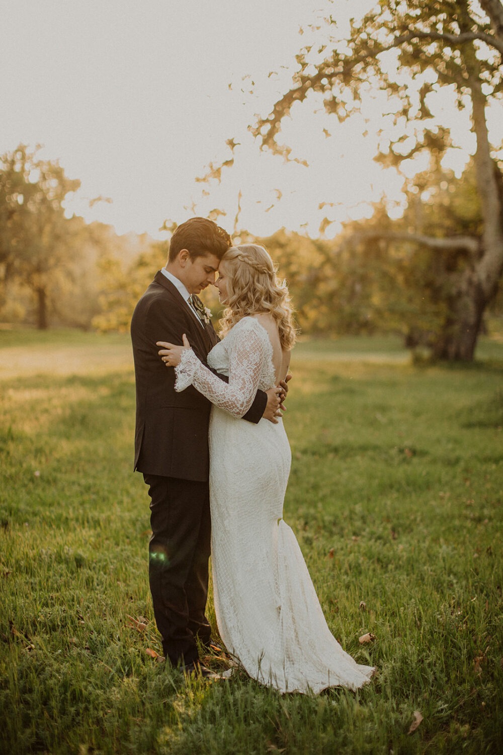 couple embrace in grassy field at sunset