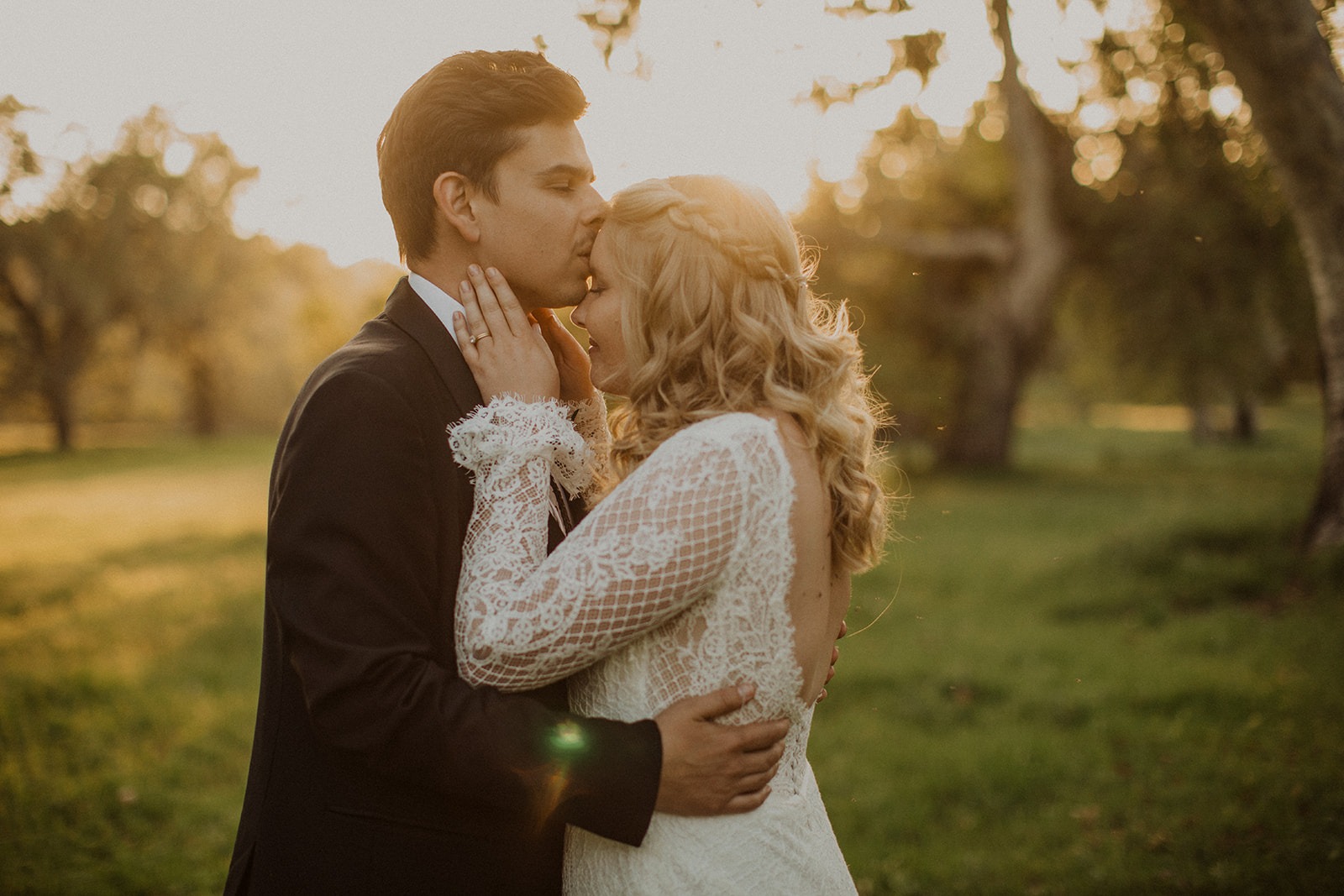 couple kiss in green grassy field at sunset