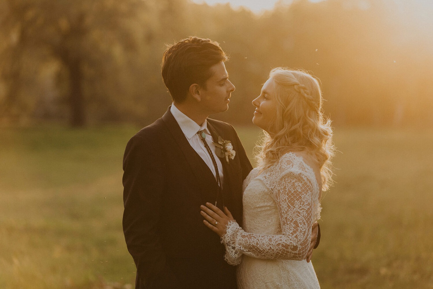 couple pose in grassy field at sunset