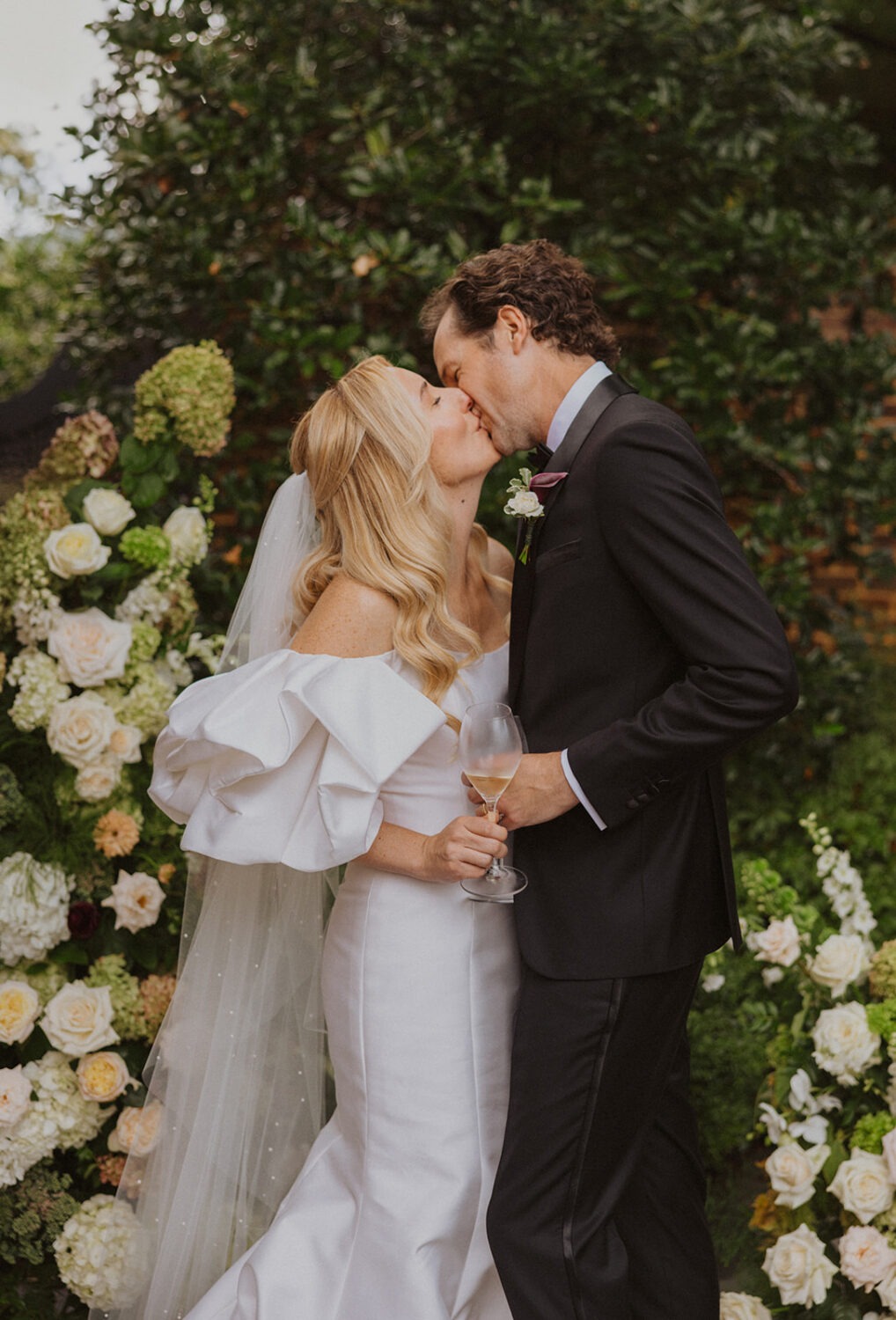 couple kissing in front of white flowers