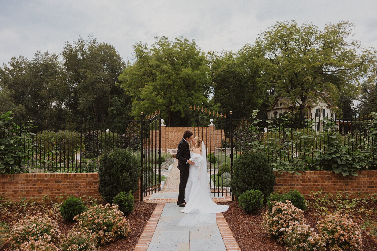 couple kiss in front of gate at the Garden of scents 