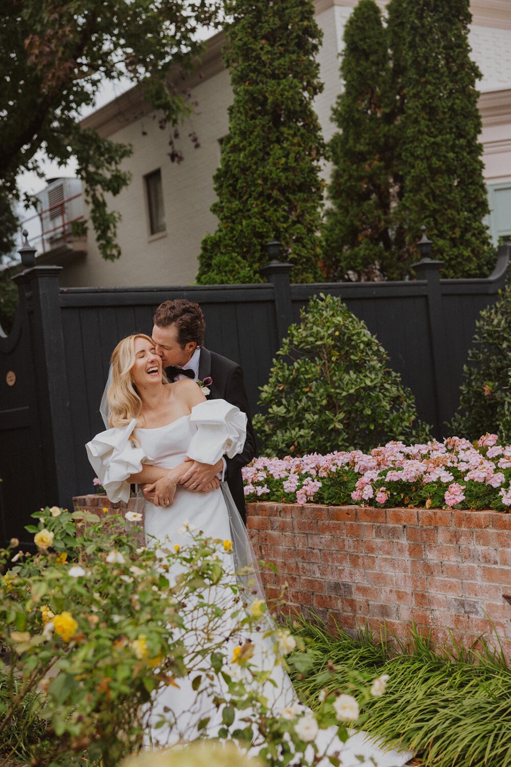 couple kiss and laugh together surrounded by flowers