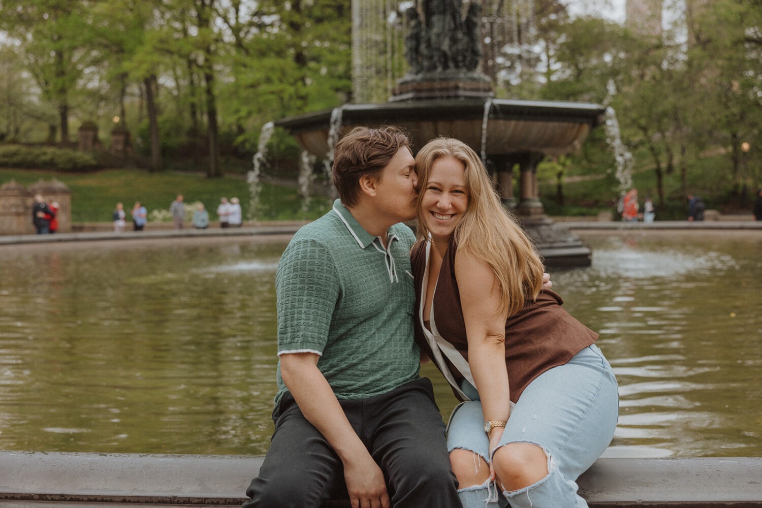 couple kiss while sitting by the Bethesda Fountain