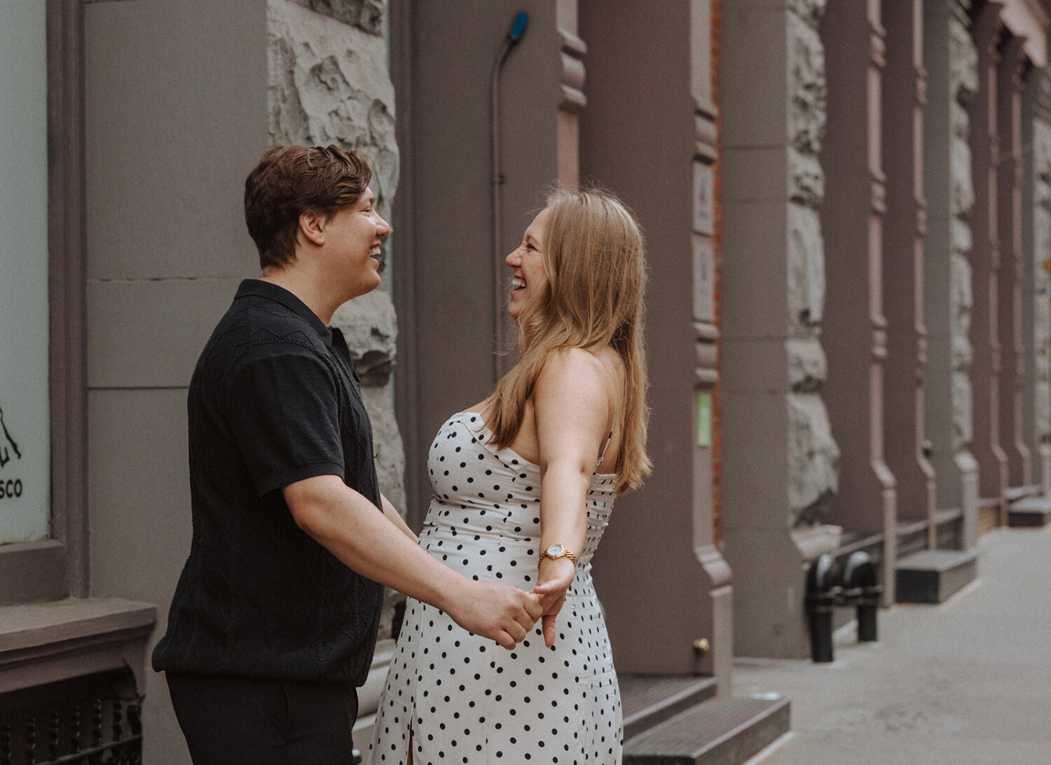 couple pose laughing together along the sidewalks of NYC