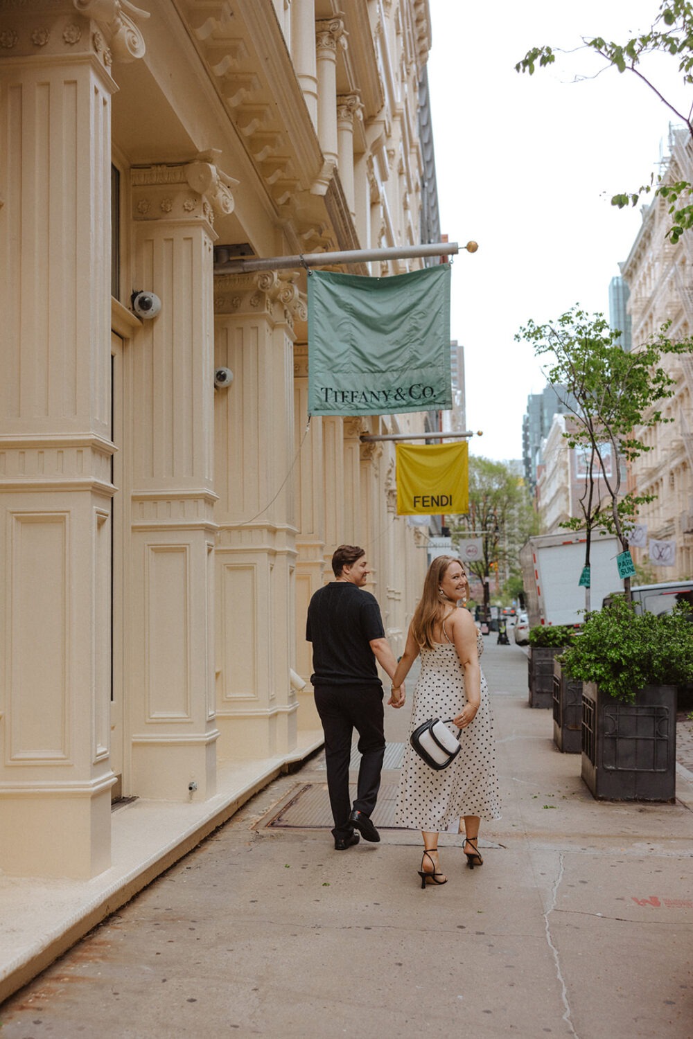 couple walking on the sidewalks of NYC during rainy engagement photos