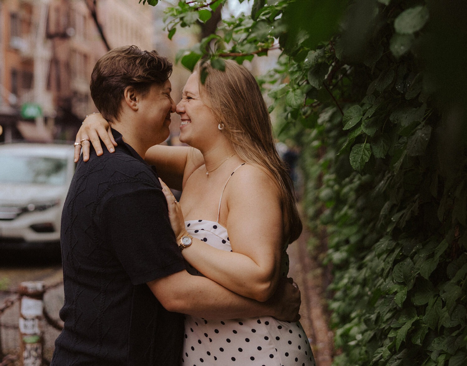 couple put noses together during rainy engagement photos
