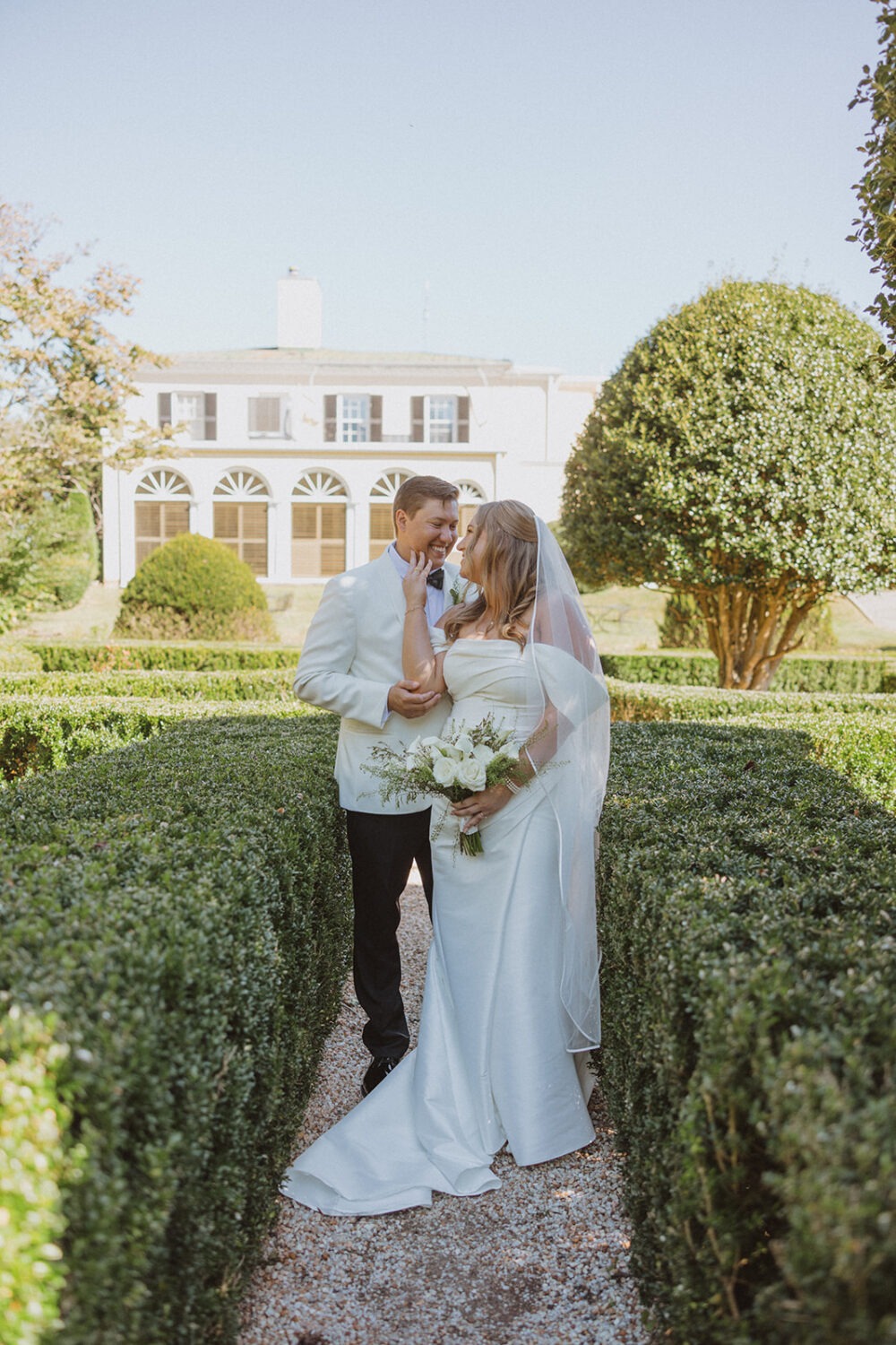 couple pose in between bushes at Airlie wedding venue