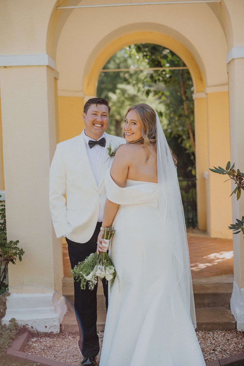 couple pose together below arches