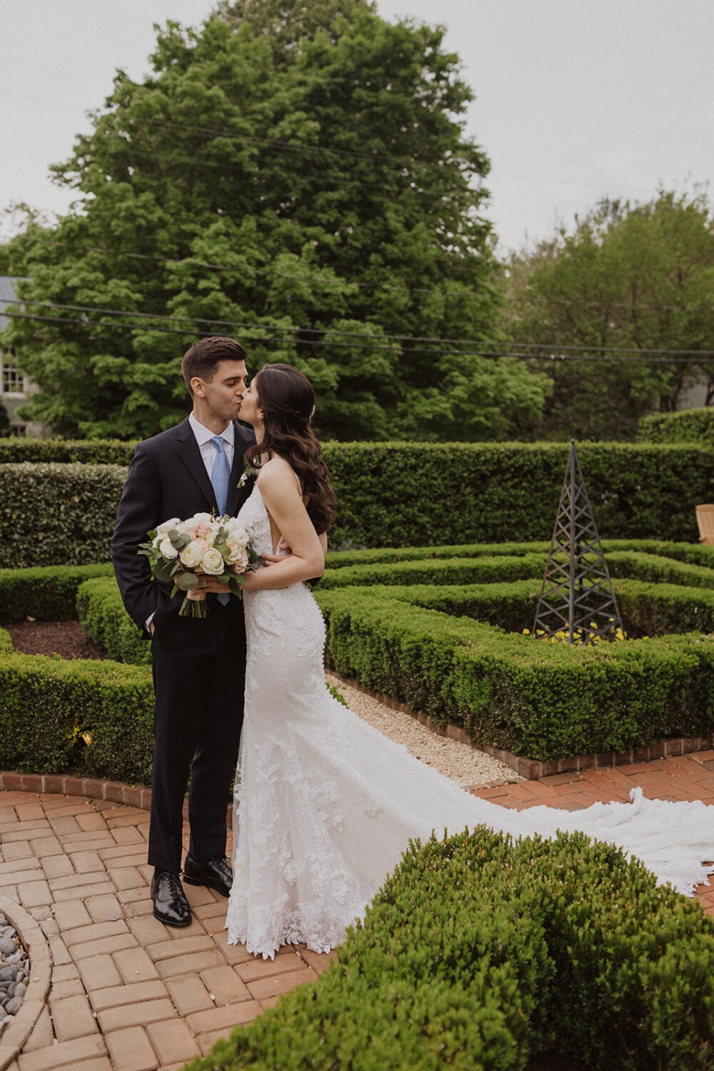 couple kiss in the courtyard with hedges