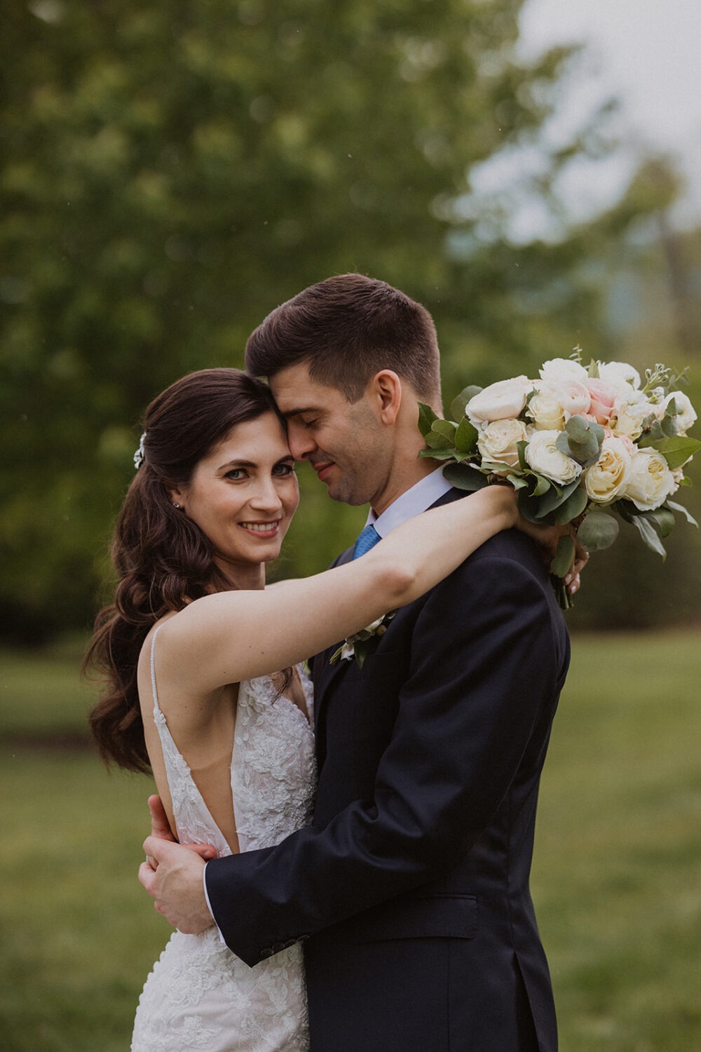 couple pose with wedding florals in the open green field