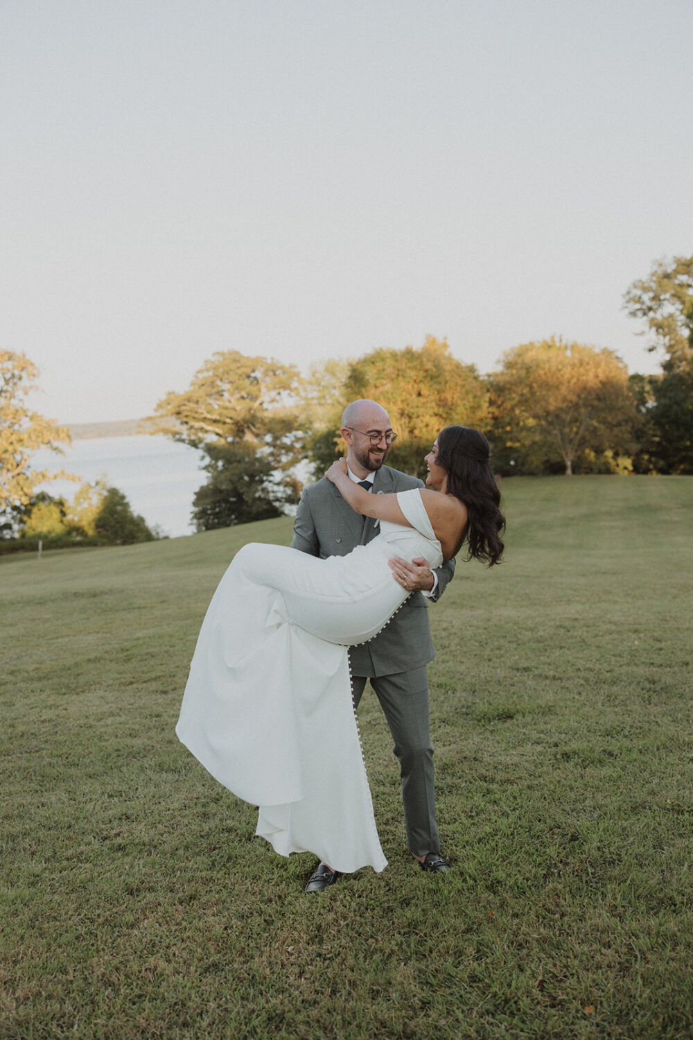 groom holding bride in front of water at River Farm Alexandria Virginia