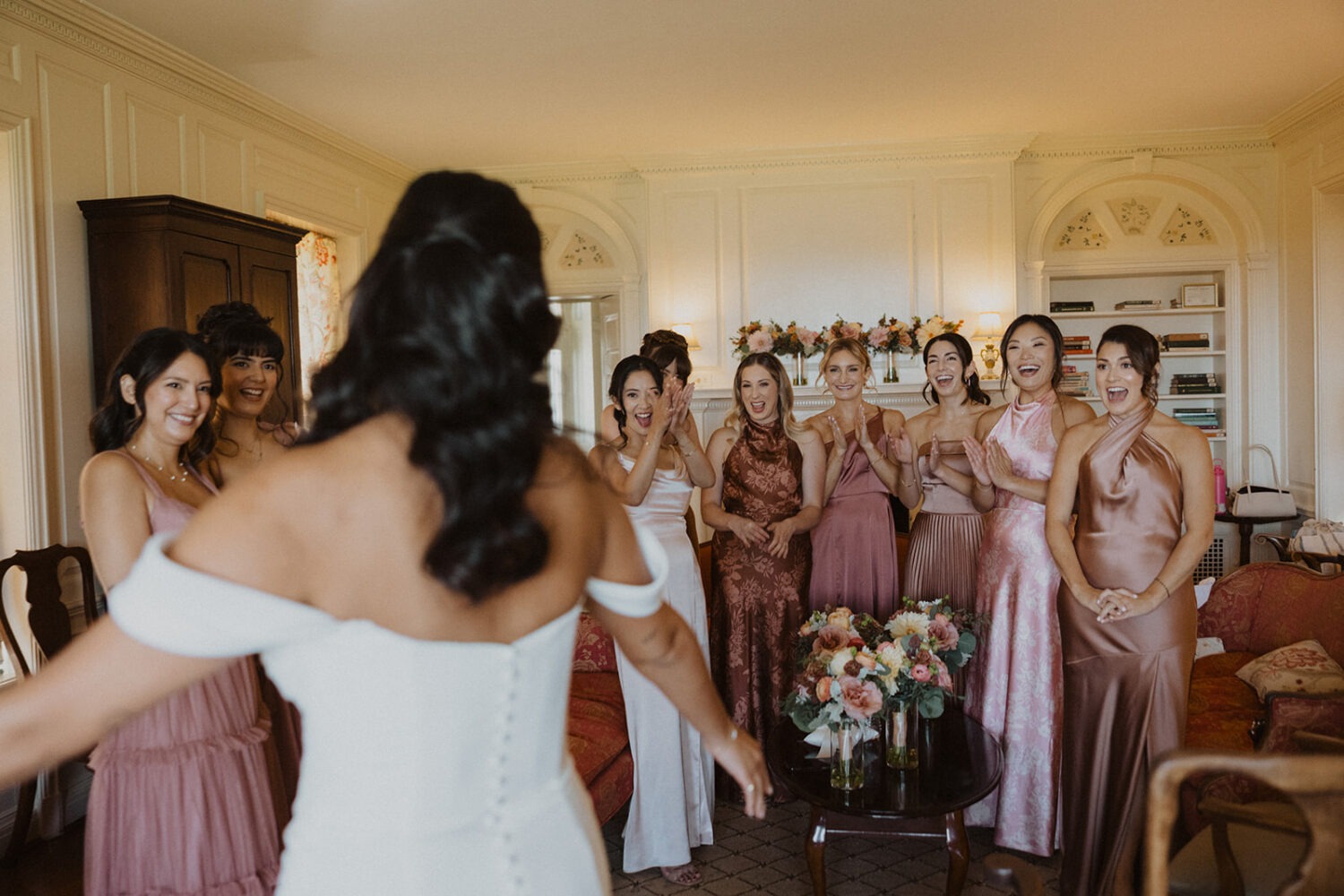bride revealing wedding dress to bridesmaids