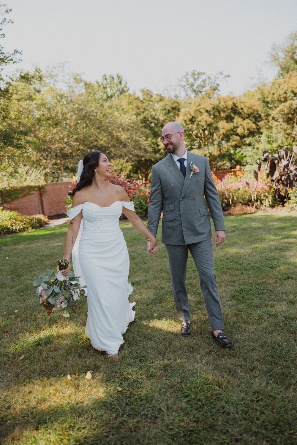 couple walking holding hands through garden