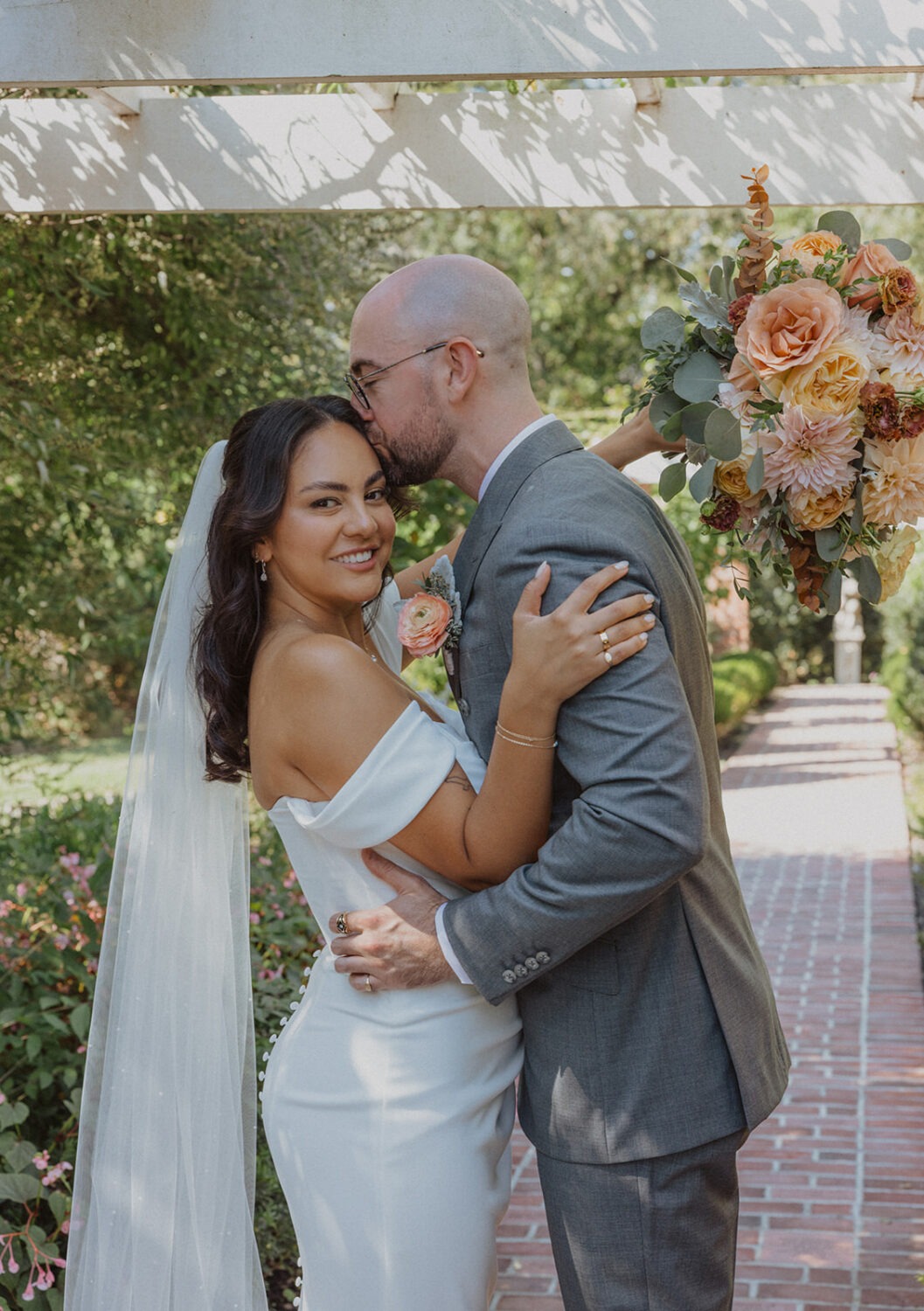 couple kiss and pose along pathway holding wedding florals at River Farm Alexandria Virginia