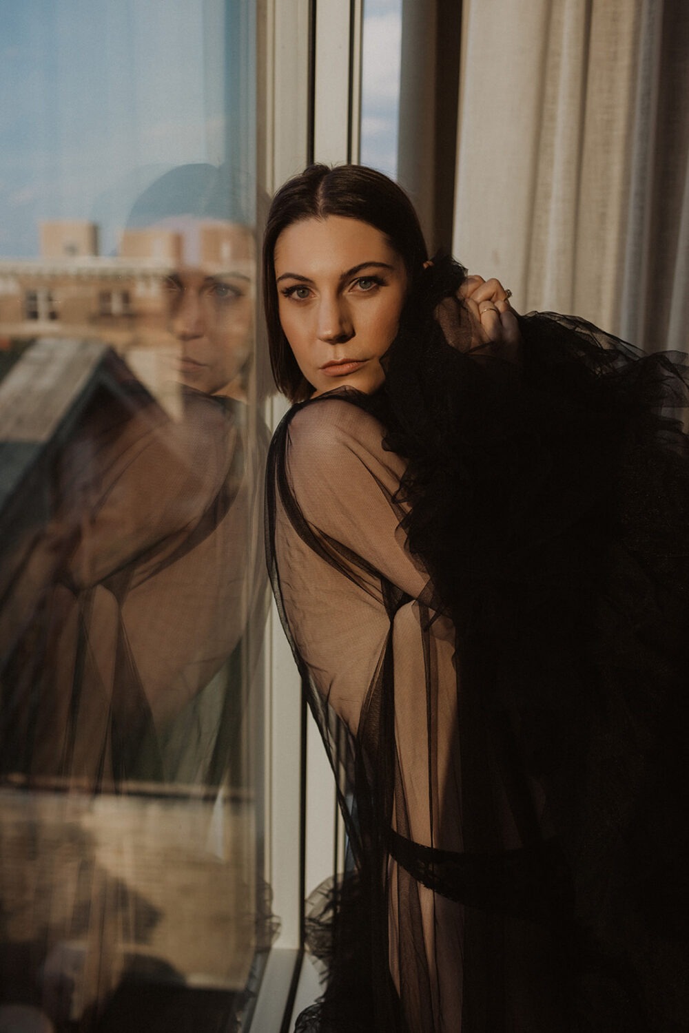 woman wears black sheer clothing in boudoir session