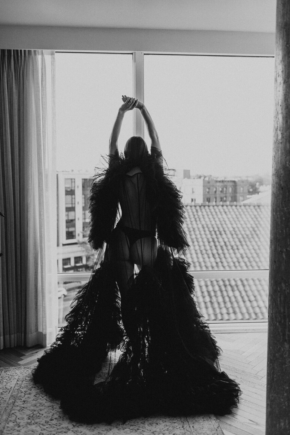 woman stands in front of window at boudoir session