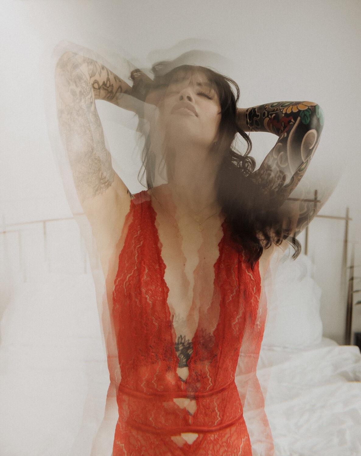 woman in red lingerie with tattoos poses on bed
